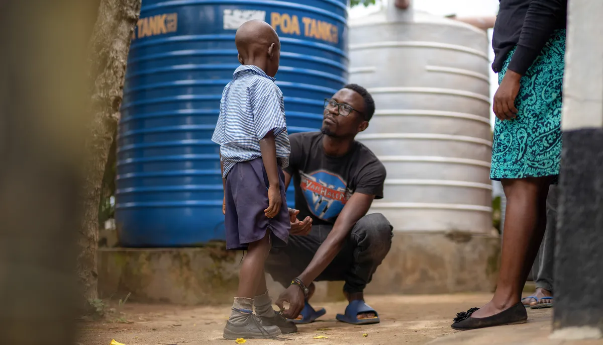 A dad crouches to tie his son's shoe