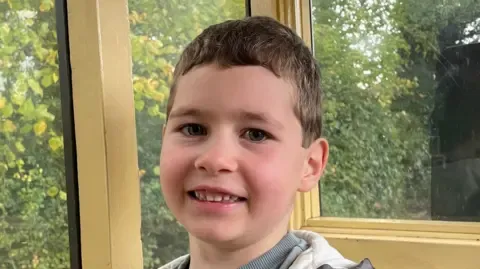 A close-up head and shoulders image of a young boy. He is smiling and looking into the camera.