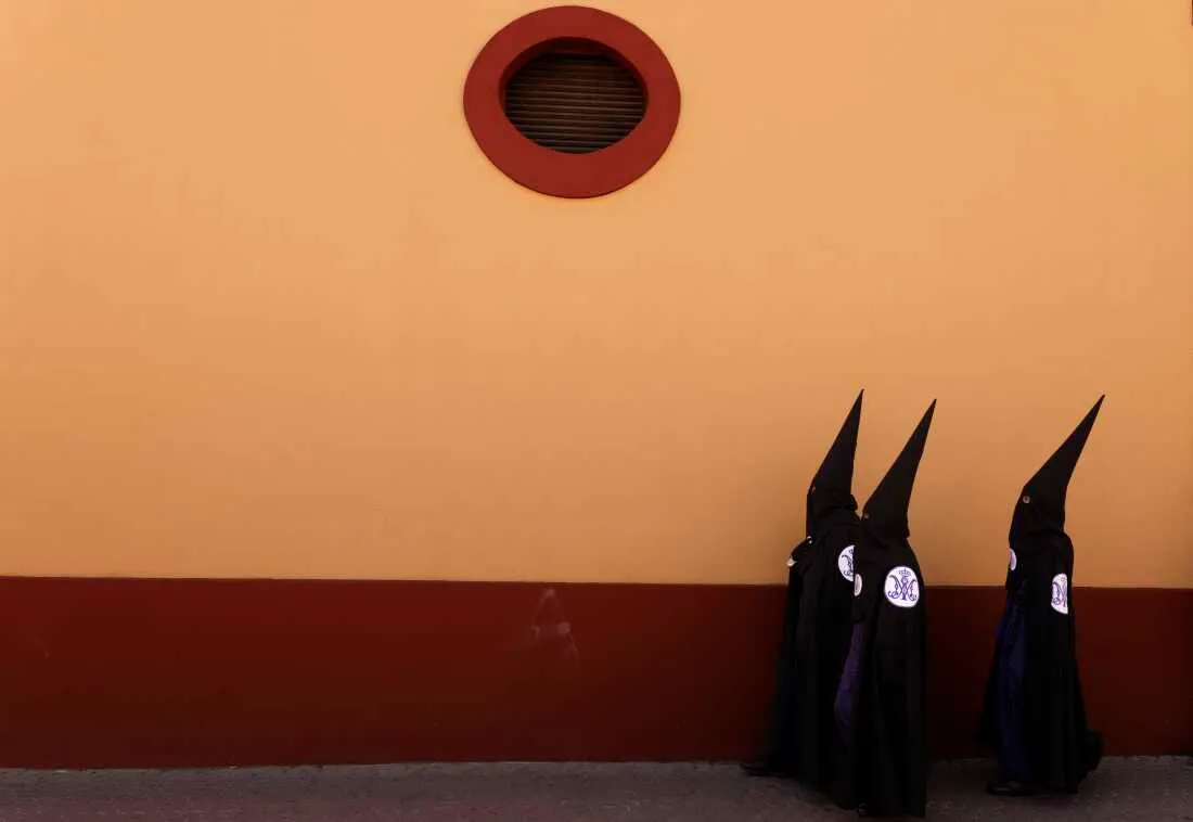 Penitents of San Bernardo brotherhood walk to their church before taking part in a procession during Holy Week
