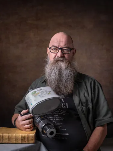 A man holds a camera and rests his arm on a book