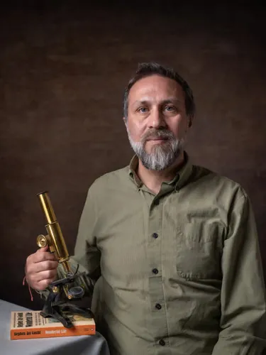A man holds a microscope that rests on a book
