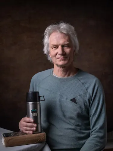 A man holds a flask that rests on a book