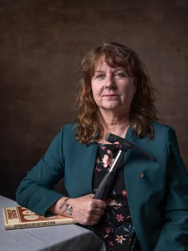 A woman clutches a hammer and rests her arm on a book