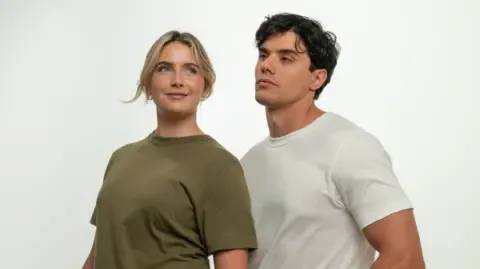 A blonde female model wears a green t-shirt and a dark-haired male model wears a white t-shirt.