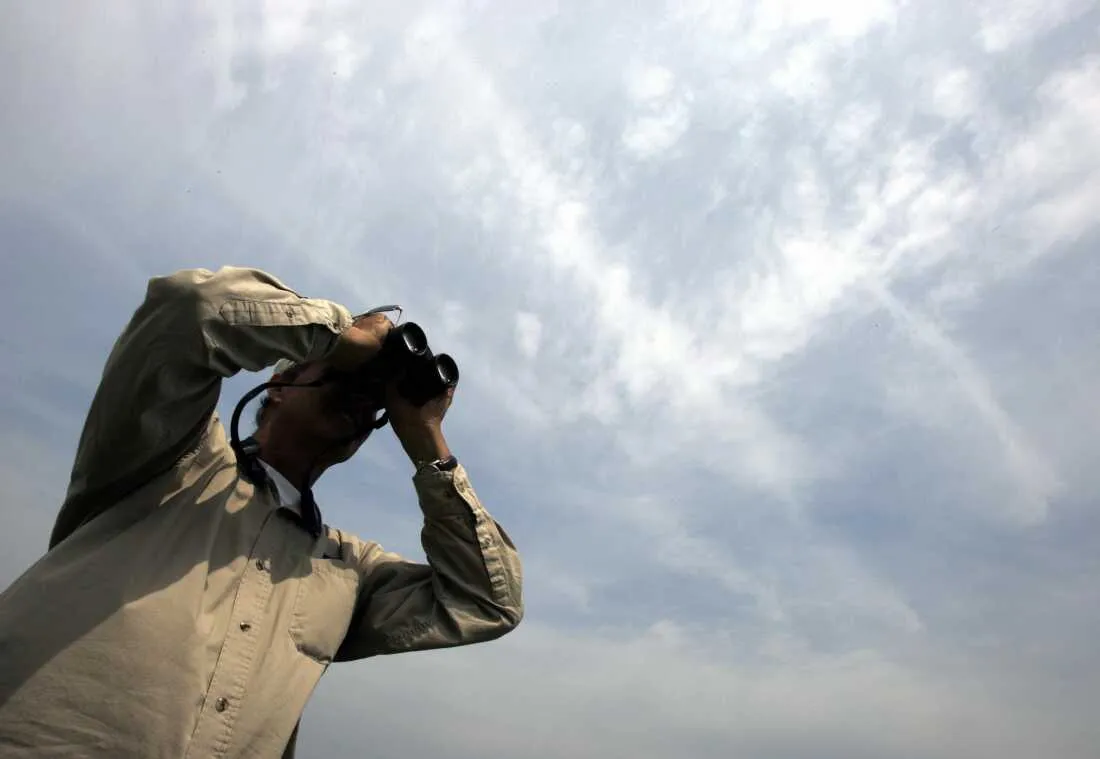 Pete Dunne uses binoculars during the World Series of Birding in an estuary in Cape May in 2007. He founded the event in 1984.