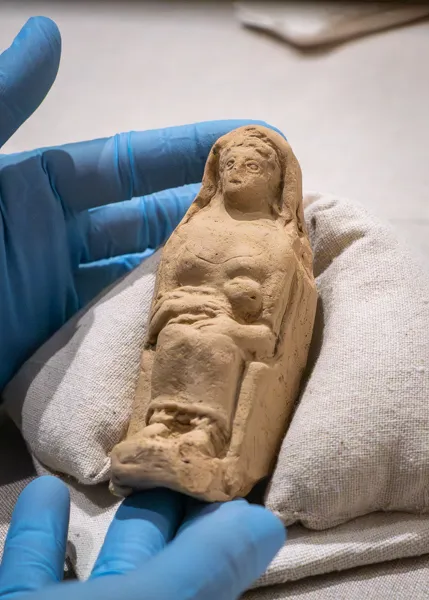 hands hold a figurine of a woman and baby