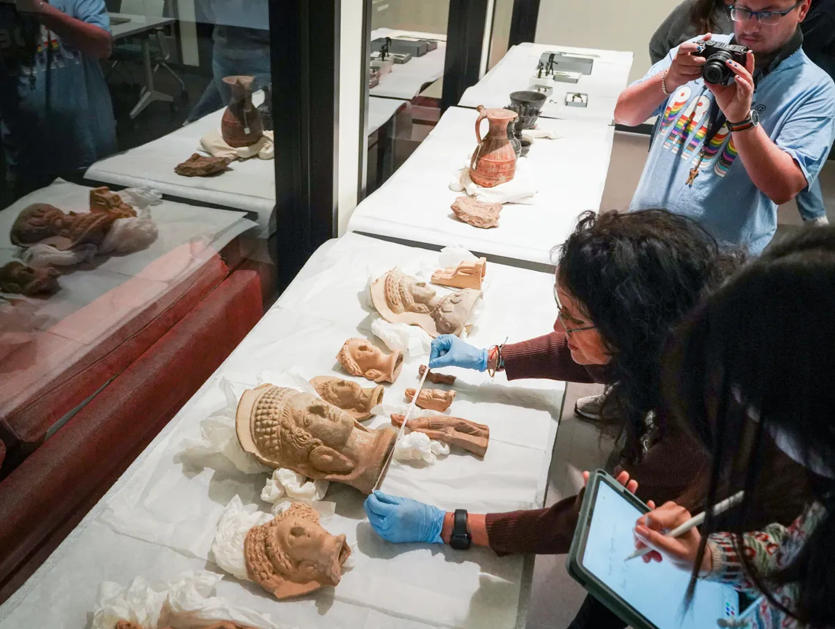 people lean over terracotta items on a table