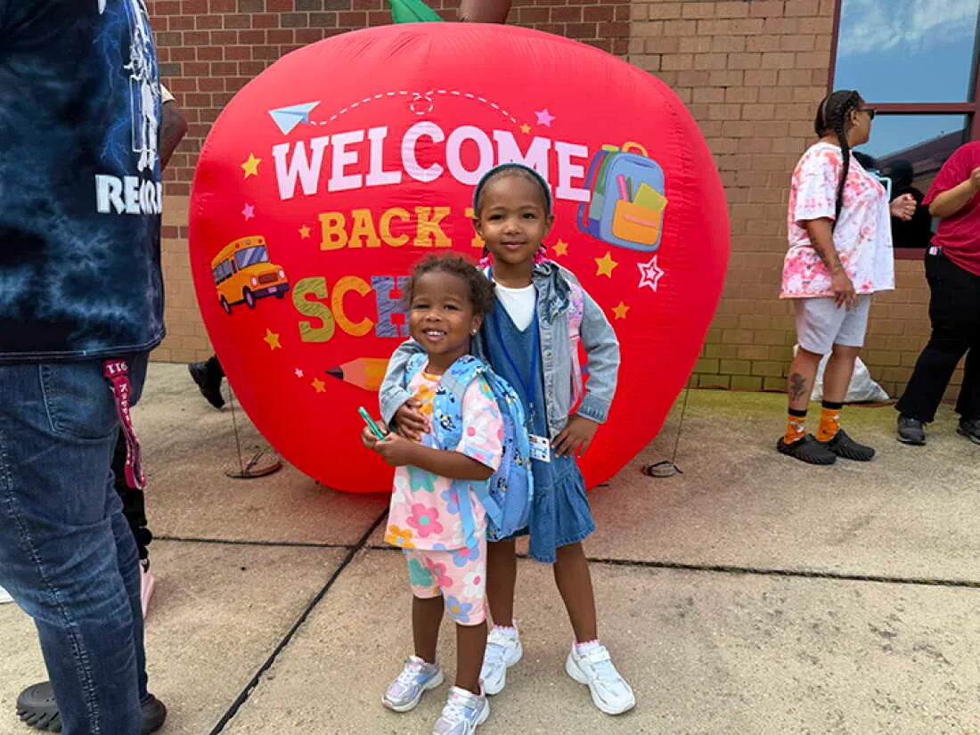 4-year-old Olivia Person stands outside Charles City Elementary on her first day of school with her 2-year-old sister Aria.