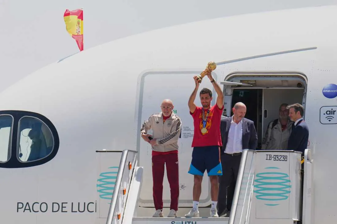 Spain's Rodrigo Hernandez lifts the World Cup trophy alongside Spain head coach Luis de la Fuente, left, and Royal Spanish Football Federation President Rafael Louzan as they arrive at Madrid airport on Monday, July 20, 2026, after Spain defeated Argentina in the World Cup final.