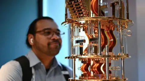 A bystander looks at the gold electronics of an IBM quantum computer