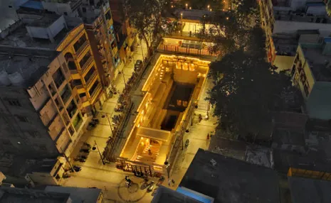 Aerial view of brightly lit stepwell at dusk surrounded by buildings
