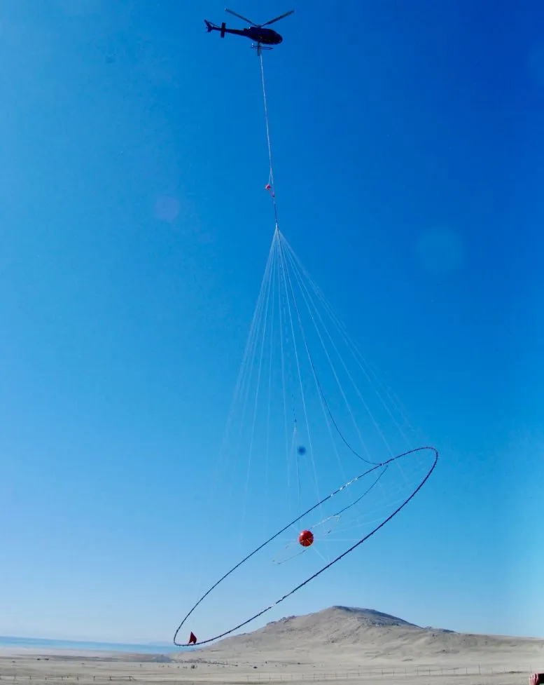 A helicopter lifts off from Antelope Island carrying electromagnetic survey equipment for a geophysical data-gathering mission over Farmington Bay in February 2025.