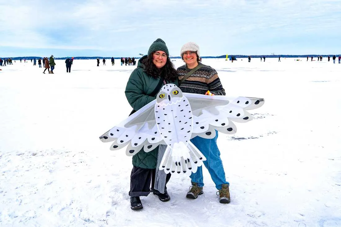 Tannia Serna (left) and Madeline Sudnick pose for a portrait with an owl kite on Lake Mendota during the annual Frozen Assets Festival.