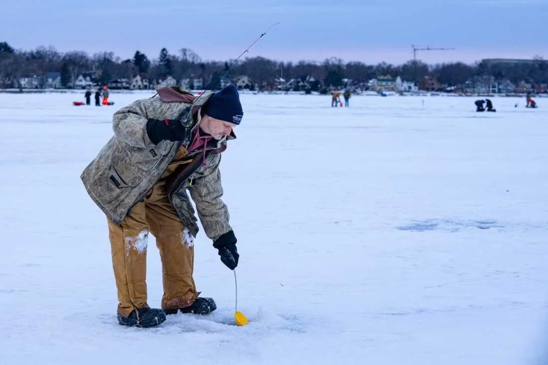 Tony Pavlak scoops slush off the water's surface in a hole drilled on Monona Bay while ice fishing.