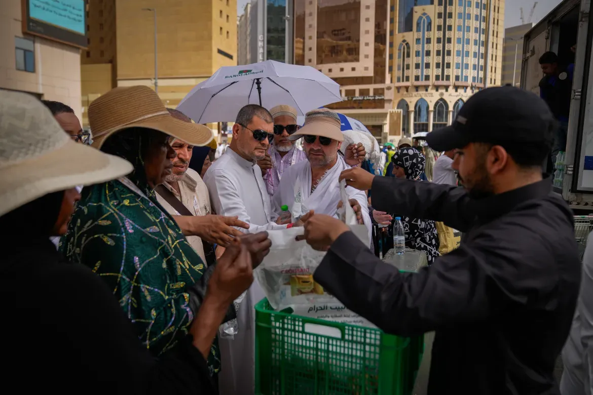 A volunteer distributes water and snacks to Muslim pilgrims.