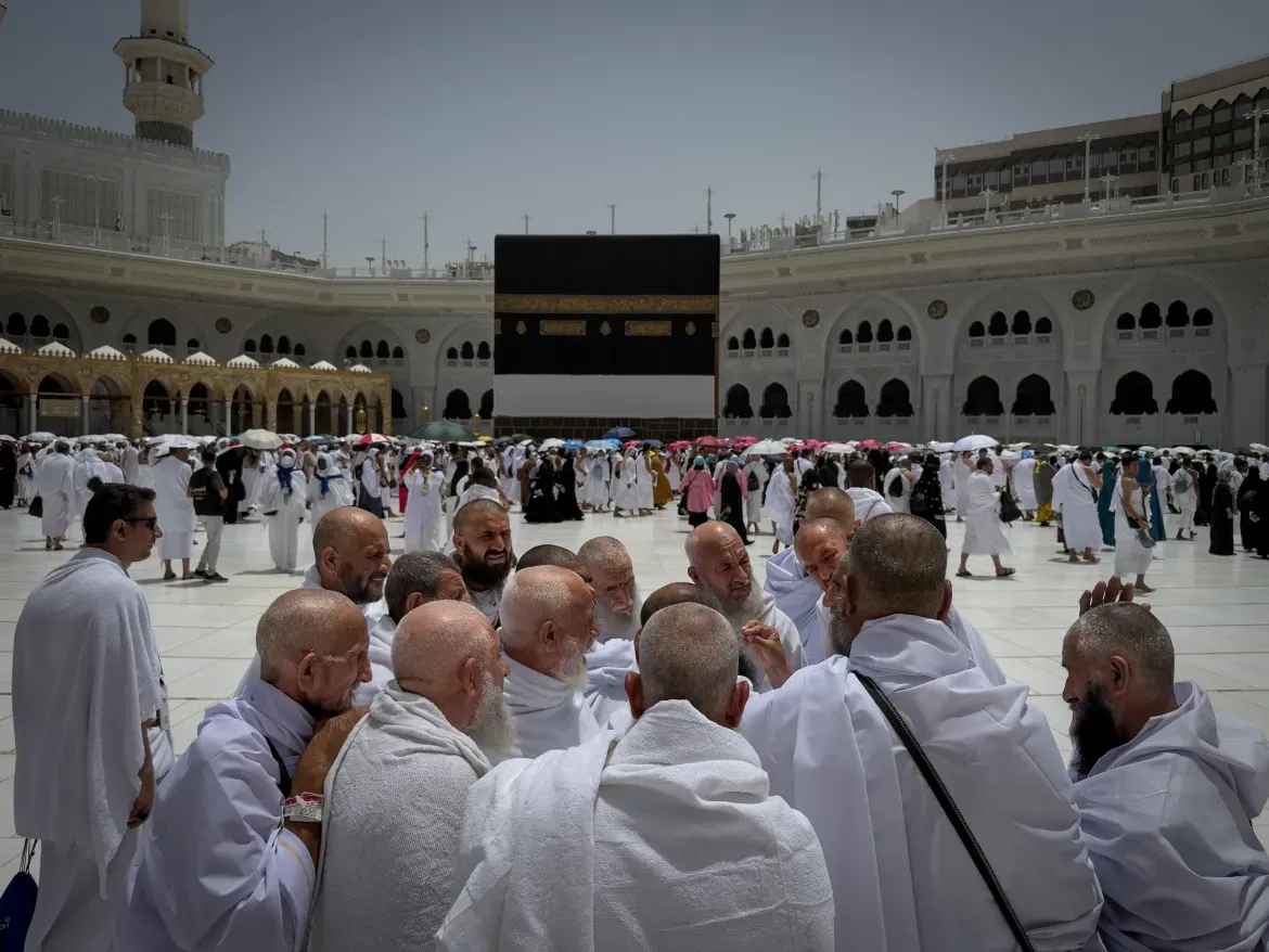 A group of Muslim pilgrims discuss the rituals of circumambulating the Kaaba.