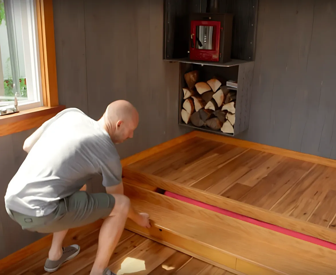 The Adirondack tiny house's bed is pulled out from under the floor