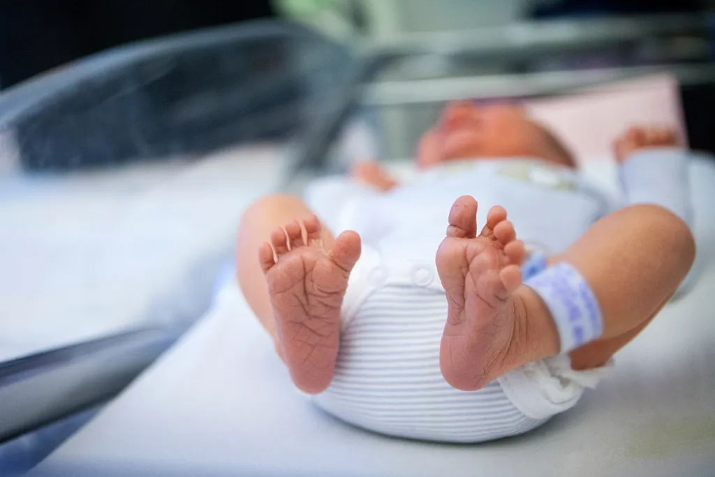 A baby's foot being pricked for a blood sample