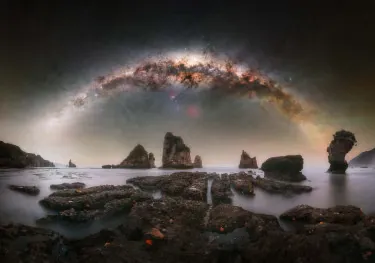 A setting Milky Way core photographed from a beach, with the starfish-covered reef offering a distinctive and compelling foreground. Due to the changing tide, the upper rows of the sky panorama were photographed from the beach, while the lowest row was captured from the reef to maintain proper alignment and perspective in the final composition